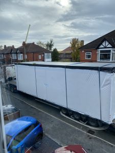 The modular materials are transported down a residential street ready for construction.